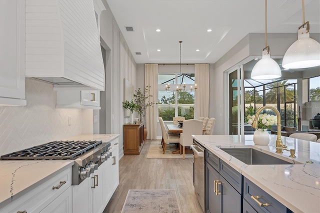 8209 Redonda Loop, Lakewood Ranch, FL 34202 - kitchen featuring appliances with stainless steel finishes, custom range hood, light wood-style floors, backsplash, and a chandelier