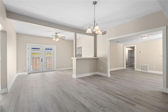 719 22nd St W, Bradenton, FL 34205 - unfurnished living room featuring light wood-style floors, a chandelier, a ceiling fan, and french doors
