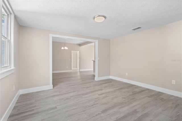 719 22nd St W, Bradenton, FL 34205 - empty room featuring light wood-type flooring, a textured ceiling, and a chandelier