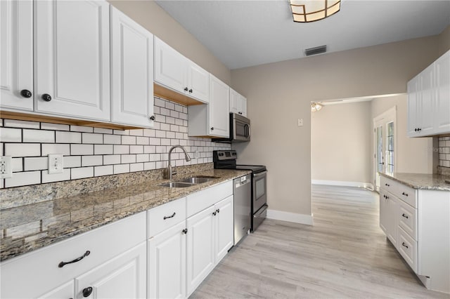 719 22nd St W, Bradenton, FL 34205 - kitchen with appliances with stainless steel finishes, tasteful backsplash, white cabinetry, light stone countertops, and light wood-style flooring