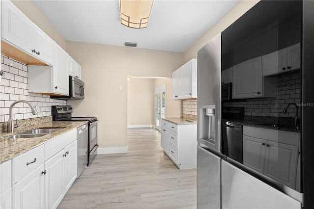 719 22nd St W, Bradenton, FL 34205 - kitchen with appliances with stainless steel finishes, tasteful backsplash, white cabinets, light stone countertops, and light wood finished floors