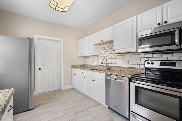 719 22nd St W, Bradenton, FL 34205 - kitchen with appliances with stainless steel finishes, white cabinets, light stone counters, light wood-type flooring, and tasteful backsplash