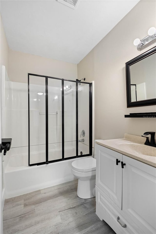 719 22nd St W, Bradenton, FL 34205 - full bath featuring vanity, shower / bath combination with glass door, and wood finished floors
