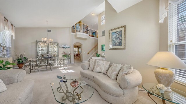 7915 Kavanagh Ct, Sarasota, FL 34240 - living area featuring stairs, carpet floors, a chandelier, arched walkways, and a high ceiling