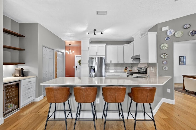 13640 2nd Ave E, Bradenton, FL 34212 - kitchen with appliances with stainless steel finishes, wine cooler, a peninsula, under cabinet range hood, and light wood-type flooring