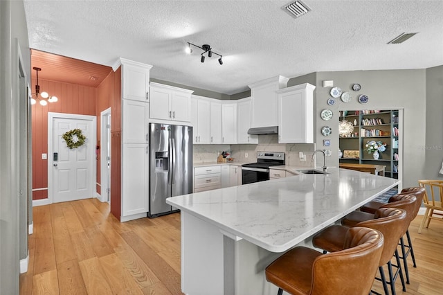 13640 2nd Ave E, Bradenton, FL 34212 - kitchen with appliances with stainless steel finishes, a peninsula, under cabinet range hood, light wood-type flooring, and white cabinets