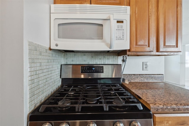 1404 Dartmouth Dr, Bradenton, FL 34207 - kitchen with stainless steel range with gas stovetop, white microwave, tasteful backsplash, and dark countertops
