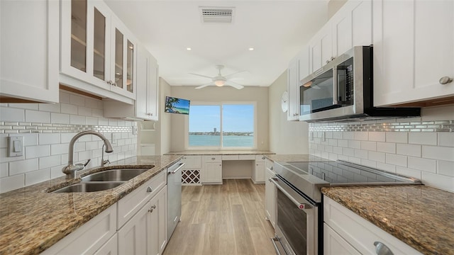 350 Golden Gate Pt Unit 61, Sarasota, FL 34236 - kitchen featuring appliances with stainless steel finishes, white cabinetry, light wood-type flooring, and stone counters