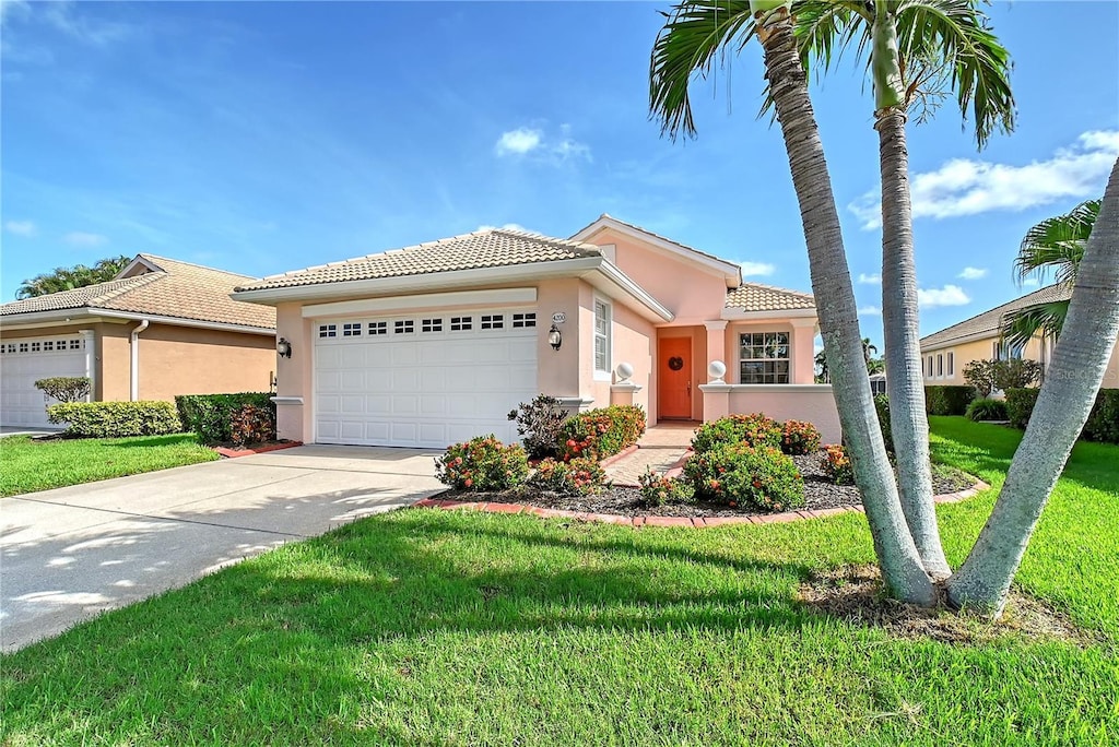 4200 Reflections Pkwy, Sarasota, FL 34233 - mediterranean / spanish-style house featuring a tiled roof, an attached garage, stucco siding, concrete driveway, and a front lawn