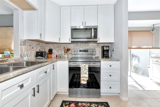 5417 Champagne Unit 63, Sarasota, FL 34235 - kitchen with appliances with stainless steel finishes, white cabinetry, decorative backsplash, and light tile patterned floors