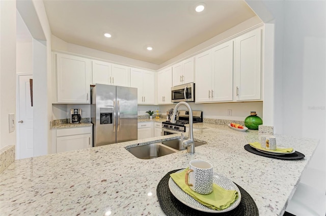 15164 Sunny Day Dr, Bradenton, FL 34211 - kitchen featuring appliances with stainless steel finishes, light stone counters, a peninsula, white cabinetry, and recessed lighting