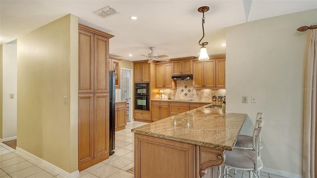 7426 Weeping Willow Blvd, Sarasota, FL 34241 - kitchen featuring a kitchen bar, under cabinet range hood, light tile patterned floors, tasteful backsplash, and black appliances