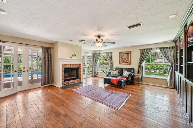 1509 Shadow Ridge Cir, Sarasota, FL 34240 - living room with a textured ceiling, french doors, ceiling fan, hardwood / wood-style flooring, and a brick fireplace