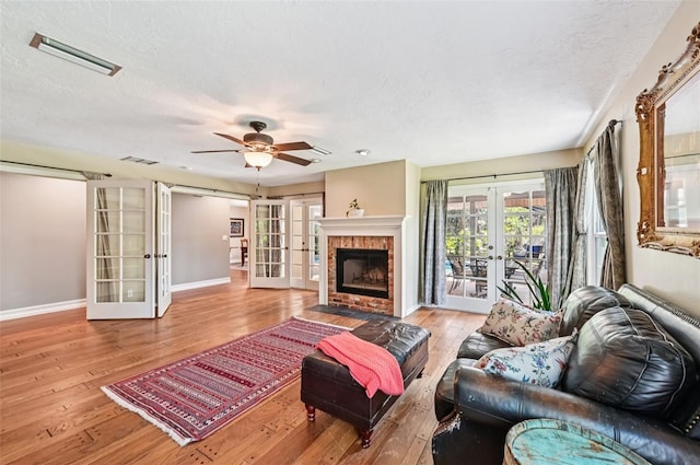 1509 Shadow Ridge Cir, Sarasota, FL 34240 - living area featuring french doors, wood-type flooring, a textured ceiling, a ceiling fan, and a fireplace