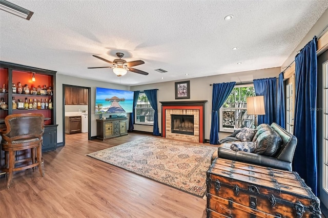 1509 Shadow Ridge Cir, Sarasota, FL 34240 - living area featuring a textured ceiling, ceiling fan, wood finished floors, a dry bar, and a fireplace