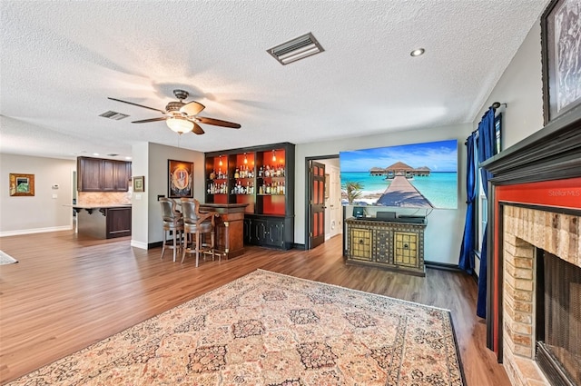 1509 Shadow Ridge Cir, Sarasota, FL 34240 - living area with a dry bar, wood finished floors, a ceiling fan, a fireplace, and a textured ceiling