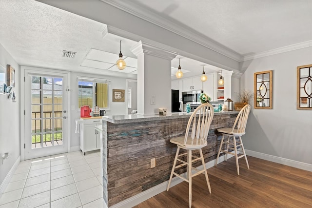 2415 Bayshore Gardens Pkwy Unit 2, Bradenton, FL 34207 - kitchen with stainless steel microwave, white cabinets, a breakfast bar, a peninsula, and wall oven
