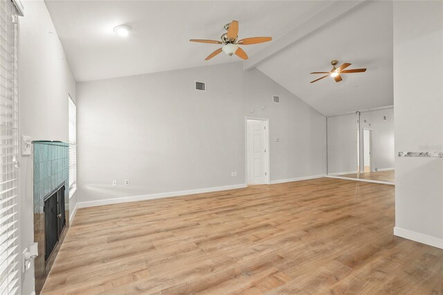 4333 Trails Dr Unit 10-1, Sarasota, FL 34232 - unfurnished living room with a ceiling fan, high vaulted ceiling, a tile fireplace, beamed ceiling, and light wood-style flooring