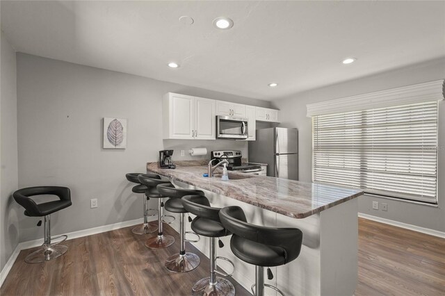 4333 Trails Dr Unit 10-1, Sarasota, FL 34232 - kitchen with stainless steel appliances, dark wood-style floors, white cabinetry, a breakfast bar, and recessed lighting