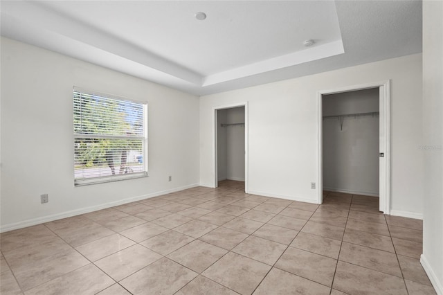 3362 Howell Pl, Sarasota, FL 34232 - unfurnished bedroom with multiple closets, a raised ceiling, and light tile patterned flooring