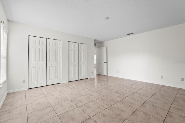 3362 Howell Pl, Sarasota, FL 34232 - unfurnished bedroom featuring two closets, light tile patterned floors, multiple windows, and a textured ceiling