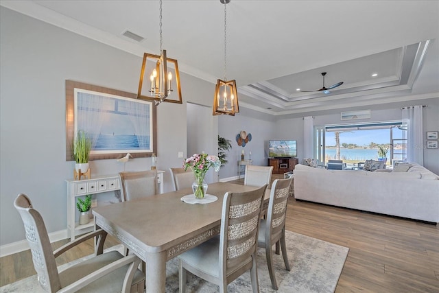 29527 Leah Rd, Punta Gorda, FL 33982 - dining area with a tray ceiling, ceiling fan, a chandelier, crown molding, and wood finished floors