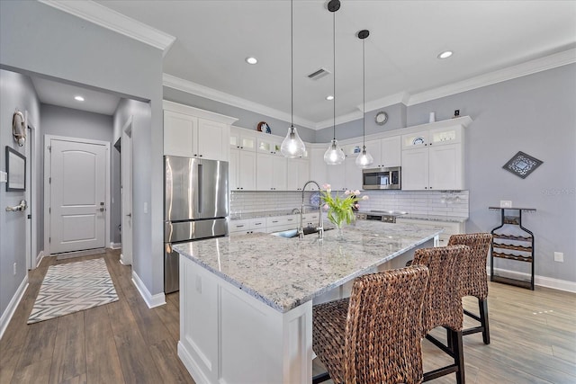 29527 Leah Rd, Punta Gorda, FL 33982 - kitchen featuring appliances with stainless steel finishes, glass insert cabinets, wood finished floors, white cabinets, and a center island with sink