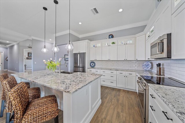 29527 Leah Rd, Punta Gorda, FL 33982 - kitchen with appliances with stainless steel finishes, ornamental molding, a breakfast bar area, recessed lighting, and glass insert cabinets