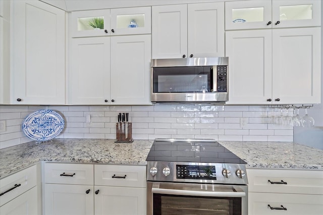29527 Leah Rd, Punta Gorda, FL 33982 - kitchen featuring appliances with stainless steel finishes, white cabinetry, decorative backsplash, and glass insert cabinets