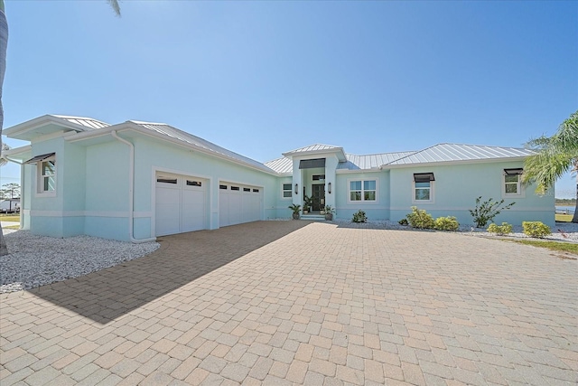29527 Leah Rd, Punta Gorda, FL 33982 - view of front facade featuring a standing seam roof, decorative driveway, stucco siding, and a garage