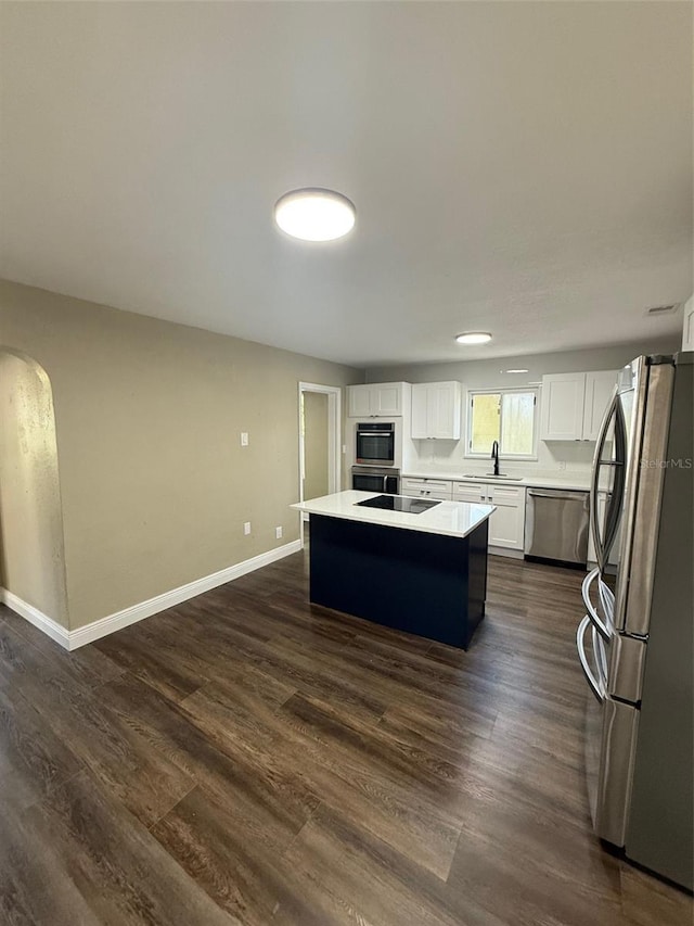 1132 26th Ave S, Saint Petersburg, FL 33705 - kitchen with stainless steel appliances, a center island, white cabinets, light countertops, and dark wood-style floors