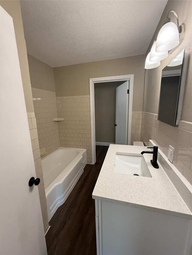 1132 26th Ave S, Saint Petersburg, FL 33705 - bathroom with wood finished floors, vanity, a tub, and a textured ceiling