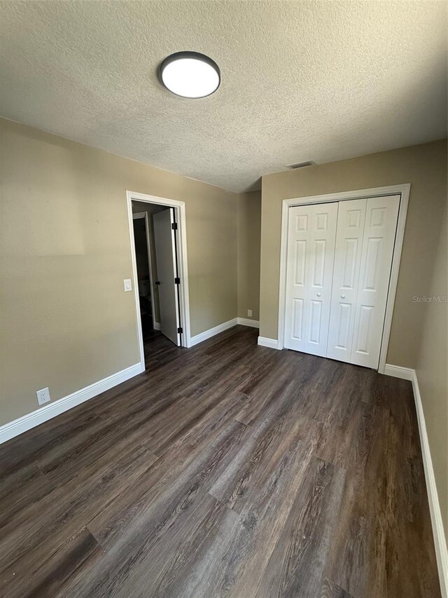 1132 26th Ave S, Saint Petersburg, FL 33705 - unfurnished bedroom featuring a textured ceiling, dark wood-style flooring, and a closet