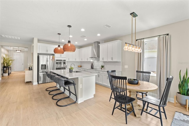 3621 Wild Blossom Pl, Parrish, FL 34219 - kitchen with stainless steel appliances, wall chimney exhaust hood, light countertops, light wood finished floors, and recessed lighting