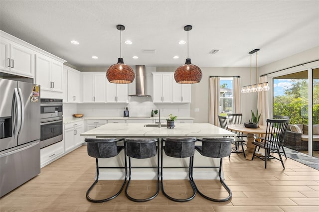 3621 Wild Blossom Pl, Parrish, FL 34219 - kitchen featuring stainless steel appliances, wall chimney range hood, light wood-type flooring, light stone counters, and recessed lighting