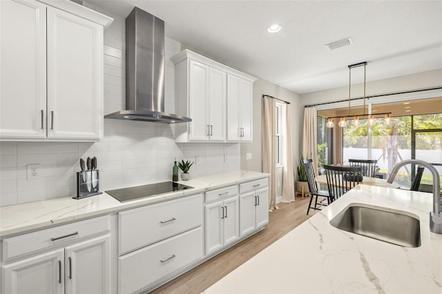 3621 Wild Blossom Pl, Parrish, FL 34219 - kitchen with wall chimney exhaust hood, black electric stovetop, white cabinets, backsplash, and decorative light fixtures