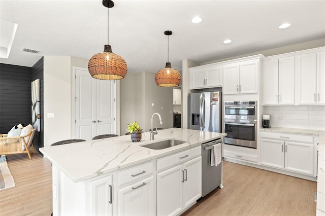 3621 Wild Blossom Pl, Parrish, FL 34219 - kitchen with stainless steel appliances, light wood finished floors, white cabinets, an island with sink, and recessed lighting