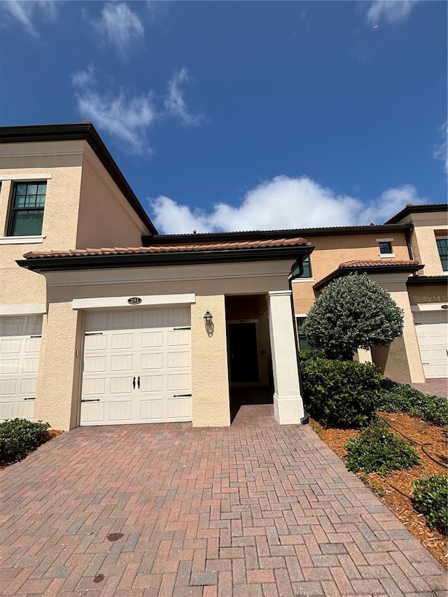 10054 Crooked Creek Dr Unit 201, Venice, FL 34293 - view of front of property featuring stucco siding, decorative driveway, and a garage