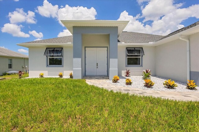10443 Riverside Rd, Port Charlotte, FL 33981 - entrance to property featuring stucco siding, a yard, and roof with shingles