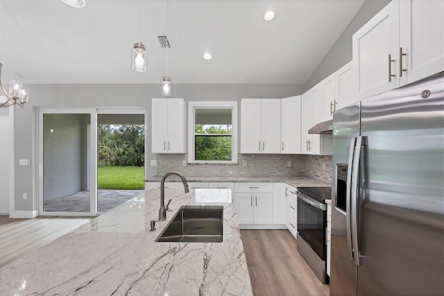 10443 Riverside Rd, Port Charlotte, FL 33981 - kitchen featuring appliances with stainless steel finishes, backsplash, light wood-type flooring, white cabinets, and vaulted ceiling
