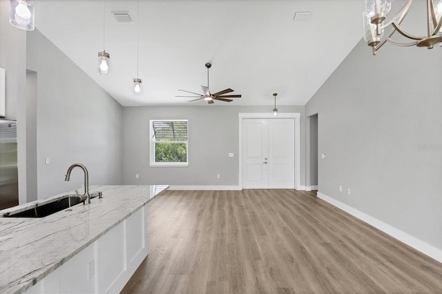 10443 Riverside Rd, Port Charlotte, FL 33981 - kitchen with lofted ceiling, light wood-type flooring, a ceiling fan, light stone countertops, and hanging light fixtures