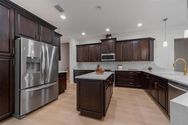 14901 17th Ave E, Bradenton, FL 34212 - kitchen featuring stainless steel appliances, crown molding, dark brown cabinetry, decorative light fixtures, and tasteful backsplash