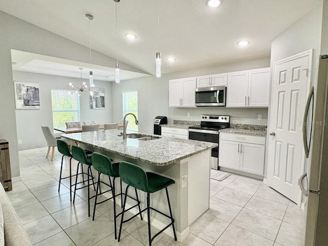 2425 Maclachlan St, Port Charlotte, FL 33953 - kitchen featuring appliances with stainless steel finishes, a kitchen breakfast bar, light stone countertops, white cabinets, and a kitchen island with sink