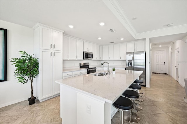850 Tidewater Shores Loop Unit 102, Bradenton, FL 34208 - kitchen with appliances with stainless steel finishes, ornamental molding, a kitchen bar, white cabinets, and a center island with sink