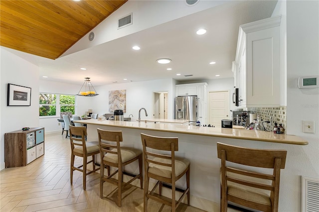 4852 Peregrine Point Cir N, Sarasota, FL 34231 - kitchen featuring stainless steel appliances, vaulted ceiling, a kitchen breakfast bar, white cabinetry, and a peninsula