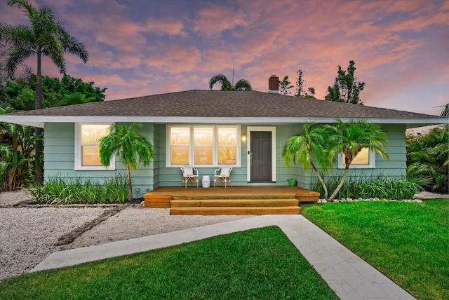 1051 Indian Beach Dr, Sarasota, FL 34234 - view of front facade featuring a front yard, a porch, a chimney, and a shingled roof
