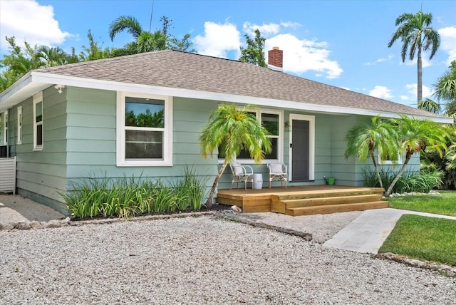 1051 Indian Beach Dr, Sarasota, FL 34234 - view of front of home featuring a shingled roof, a porch, and a chimney