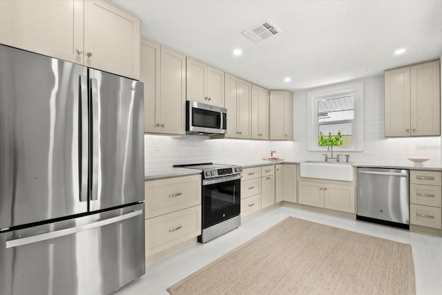 1051 Indian Beach Dr, Sarasota, FL 34234 - kitchen with stainless steel appliances, cream cabinets, backsplash, recessed lighting, and light countertops