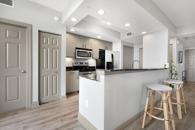 800 N Tamiami Trl Unit 405, Sarasota, FL 34236 - kitchen featuring appliances with stainless steel finishes, a peninsula, light wood finished floors, recessed lighting, and dark stone countertops