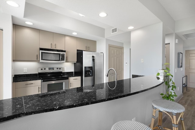 800 N Tamiami Trl Unit 405, Sarasota, FL 34236 - kitchen featuring stainless steel appliances, wood finished floors, dark stone counters, recessed lighting, and a peninsula